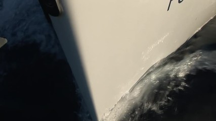 Nose and sides of white moving yacht cuts waves of water surface. Yachting sport, sea journey and regatta as an active lifestyle.