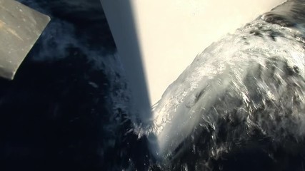 Nose and sides of white moving yacht cuts waves of water surface. Yachting sport, sea journey and regatta as an active lifestyle.