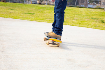 young skateboarder legs riding skateboard at skatepark.