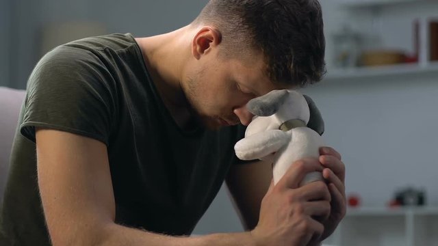 Thoughtful serviceman holding toy in hand, young father missing child, nostalgia
