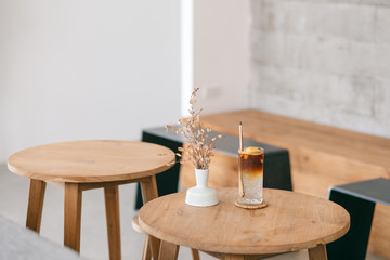 Closeup image of a glass of iced coconut coffee on wooden table in minimal cafe