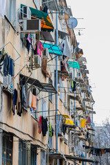 Fototapeta na wymiar Photo of the facade of a high-rise building in a poor neighborhood with lots of clothes drying out right outside the windows