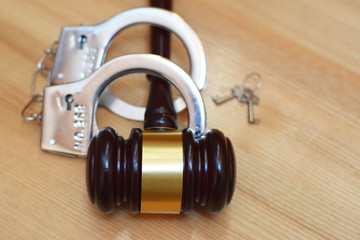 Judges gavel or law mallet, handcuffs and key on light wooden background with copy space. Judgement, legal system, time for justice concept.