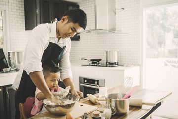 happy family in kitchen. Father and son knead dough and bake the bakery together