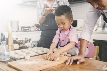 Fototapeta premium happy family in kitchen. family knead dough and bake the bakery together in kitchen
