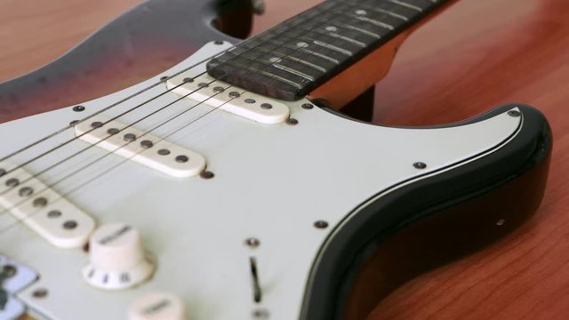 Slide motion of old electric guitar with a fine pattern of guitar strings placed on a wooden floor table