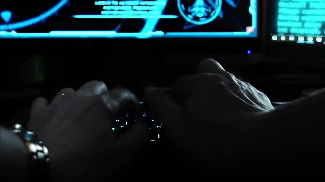 Close up of the hands of a hacker cyber criminal, typing rapidly on a keyboard