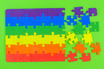 equality propaganda: LGBT flag color puzzle ripped apart on green background