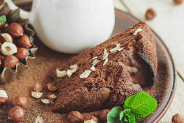 Piece of chocolate cake, mint leaves, hazelnuts and jar with milk