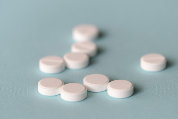 White tablets scattered on a blue background close up