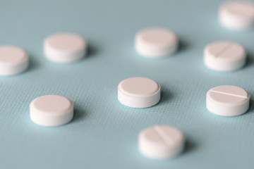 White tablets scattered on a blue background close up