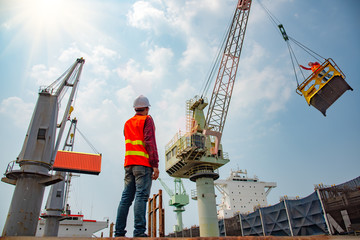 stevedore or foreman, engineering, loading master talks to crane driver by walkie talkie for safety...