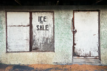 Fototapeta na wymiar Facade of a rundown shop with closed wooden window and door at the market in Leon, Iloilo province, Philippines. Ice for sale is written on the window