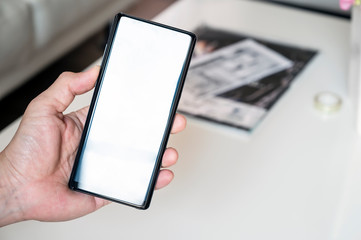 Closeup man hand holding smartphone with blank screen, copy space for text or product display.