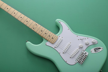 緑色の背景に置いたパステル緑色のエレキギターストラトキャスター