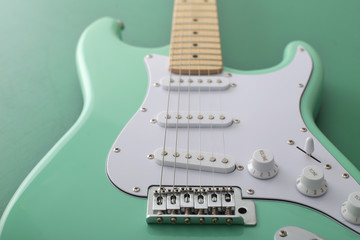 緑色の背景に置いたパステル緑色のエレキギターストラトキャスター