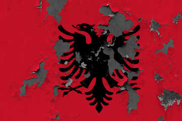 Close up grungy, damaged and weathered Albania flag on wall peeling off paint to see inside surface.
