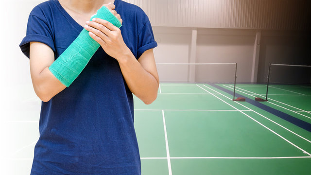 badminton player hand wrist injury on background badminton indoor court, sport accident pain concept