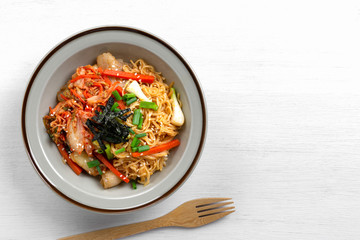 top view of stir fried egg noodles with kimchi in a ceramic dish. asian homemade style food concept.