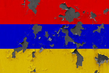 Close up grungy, damaged and weathered Armenia flag on wall peeling off paint to see inside surface.