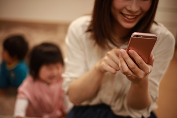 スマートフォンの操作に夢中になる母親