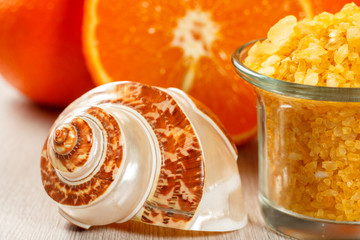 Cut orange, sea shall and glass bowl with yellow sea salt.