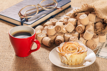 Board game lotto on sackcloth. Wooden lotto barrels in bag and game cards with notebook, cup of coffee and homemade cookie.
