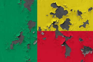 Close up grungy, damaged and weathered Benin flag on wall peeling off paint to see inside surface.