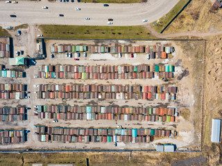 Aerial view of a large number of iron garages for cars with colored roofs standing in close to each other near the road fenced. Parking of vehicles for the night without security.