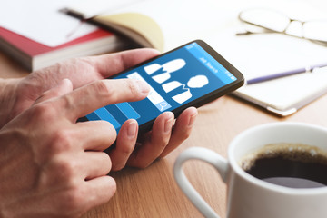 Online job search concept. Using smartphone and app.Closeup of male hands touching smartphone screen for using app at table.