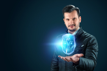 A man holds out a hand with a hologram of a robot head, artificial intelligence on a blue background. Concept neural networks, autopilot, robotization, industrial revolution 4.0.