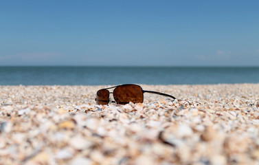 Sunglasses  lying on a beach near the blue sea, vacation and summer time, eye protection