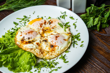 Flat lay of tasty breakfast over grey concrete table background. Fried eggs, micro greens, fresh tomatoes in plate, top view. Clean eating, dieting, vegetarian food - Image