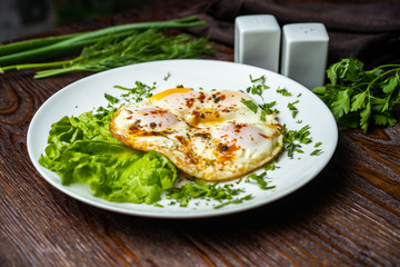 Flat lay of tasty breakfast over grey concrete table background. Fried eggs, micro greens, fresh tomatoes in plate, top view. Clean eating, dieting, vegetarian food - Image