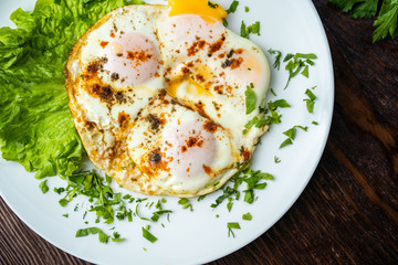 Flat lay of tasty breakfast over grey concrete table background. Fried eggs, micro greens, fresh tomatoes in plate, top view. Clean eating, dieting, vegetarian food - Image