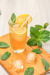 Cold refreshing summer lemonade with ice and lemon slices, decorated with mint leaves in a tall glass.