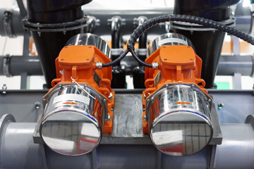 Industrial vibromotors mounted on the pipework of the system of vibrating transport