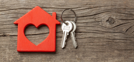 Wooden red house and keys on the old wooden boards. Copy space for text.