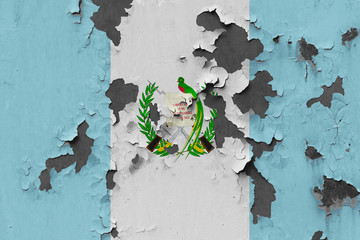 Close up grungy, damaged and weathered Guatemala flag on wall peeling off paint to see inside surface.