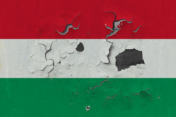 Close up grungy, damaged and weathered Hungary flag on wall peeling off paint to see inside surface.