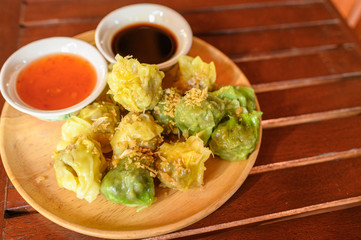 Yellow and green dumpling dim sum stuffed with pork and shrimp with sauces