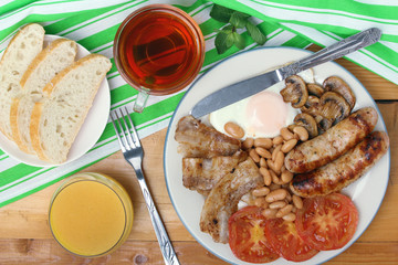 Classic English breakfast served: eggs, bacon, beans, juice and tea