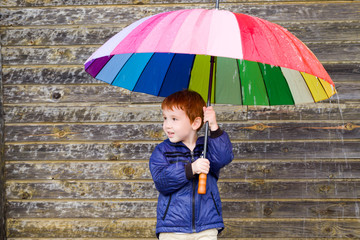 a little boy hid under a multi-colored umbrella