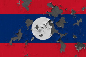 Close up grungy, damaged and weathered Laos flag on wall peeling off paint to see inside surface.
