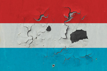 Close up grungy, damaged and weathered Luxembourg flag on wall peeling off paint to see inside surface.