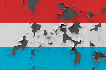 Close up grungy, damaged and weathered Luxembourg flag on wall peeling off paint to see inside surface.