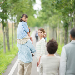 Obraz premium 一本道で肩車をする親子と祖父母