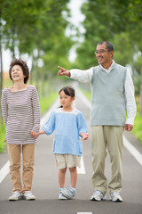 一本道で手をつなぐ祖父母と孫