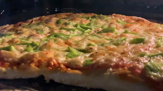 Baking tasty italian pizza in the hot owen. Delicious crispy pizza with dough, cheese, chicken breast, green bell peper and tomato sauce.