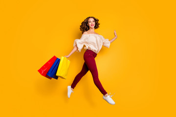 Fototapeta na wymiar Full length body size view portrait of nice attractive pretty slim fit thin careless cheerful cheery wavy-haired lady carrying colorful bags isolated over bright vivid shine yellow background